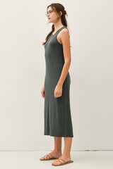 woman wearing a dark green sleeveless maxi dress with a relaxed fit and side slit, standing sideways against a neutral background