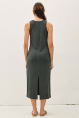 woman wearing a dark green sleeveless midi dress with a back slit detail
