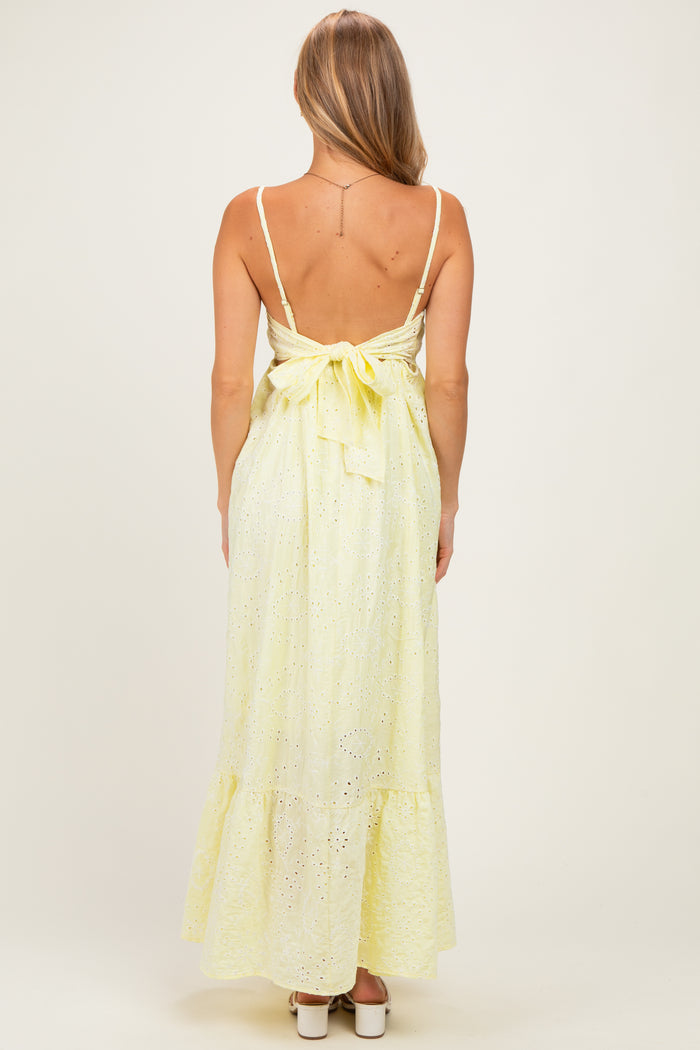 woman wearing a yellow eyelet maxi dress with a back tie detail and ruffled hem