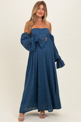 woman wearing a navy blue lace off-the-shoulder maternity dress with puff sleeves and holding her baby bump