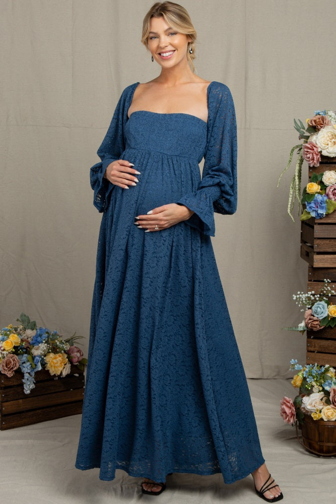 woman wearing a blue lace maternity maxi dress with long puff sleeves and holding her baby bump
