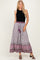 woman wearing a black sleeveless top and a long printed skirt with a tie waist and tassels