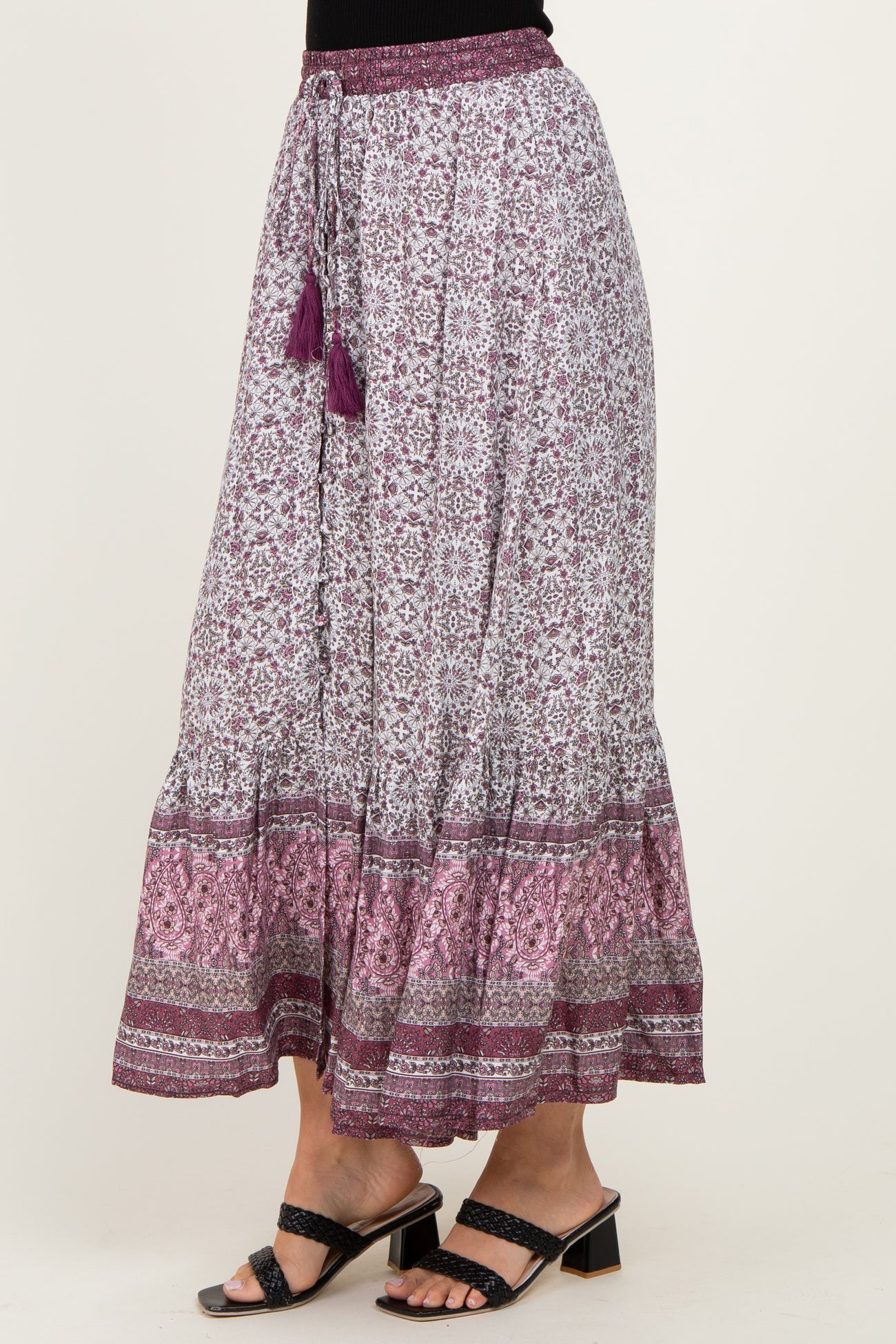 woman wearing a purple and white floral print maxi skirt with a tiered hem and tassel details