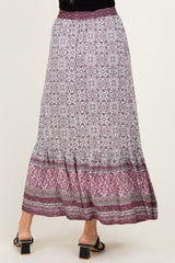 woman wearing a patterned maxi skirt with a tiered hem and a purple color palette, viewed from the back