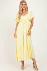 woman wearing a yellow maxi dress with flutter sleeves and a tie detail at the bust