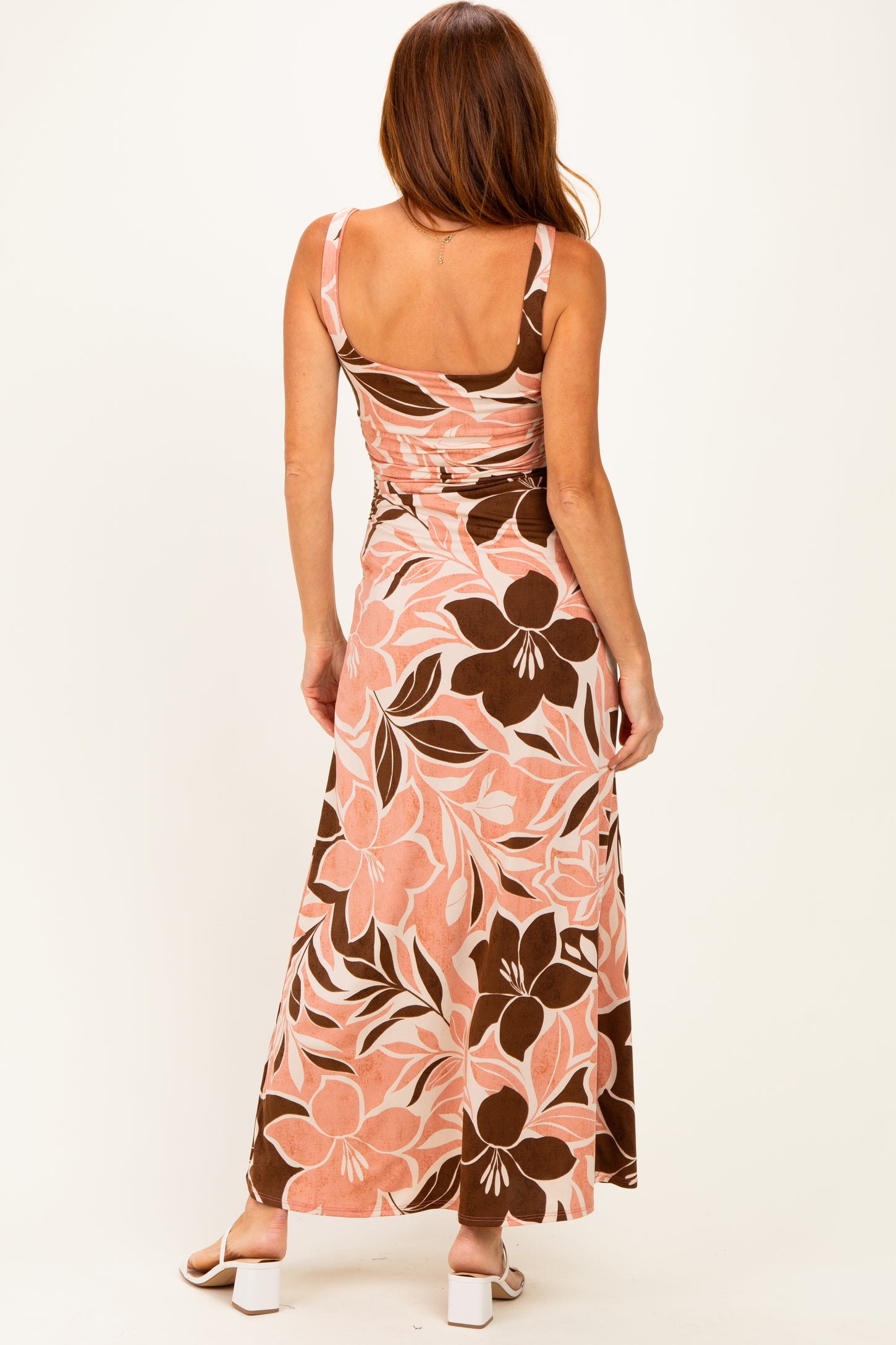 woman wearing a pink and brown floral maxi dress with a fitted bodice and a flowing skirt, seen from the back