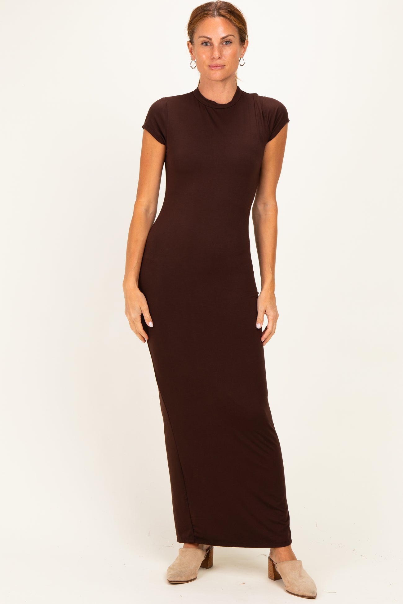 woman wearing a brown cap sleeve maxi dress standing against a light background