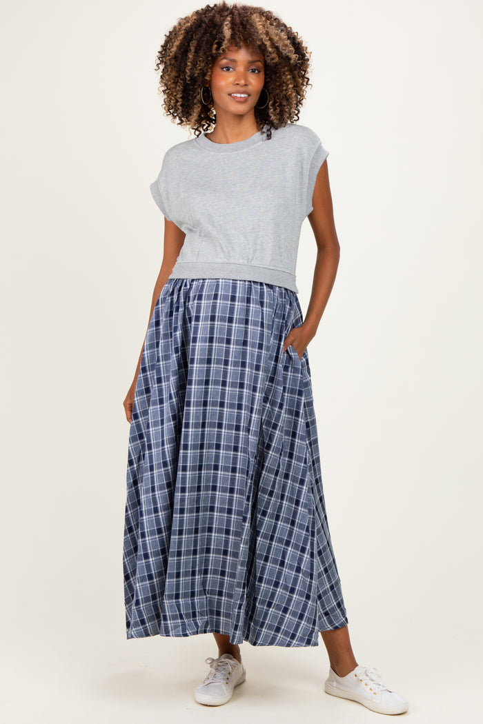 woman wearing a gray cropped maternity top and a long blue plaid maternity skirt with pockets