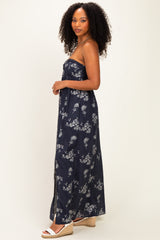 woman wearing a navy blue strapless maxi dress with white floral print and posing sideways