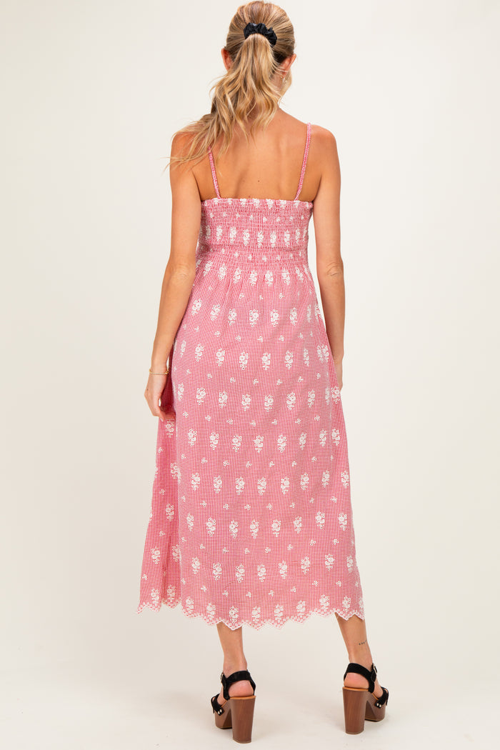 woman wearing a pink and white floral maternity midi dress with spaghetti straps and a smocked bodice, showing her baby bump