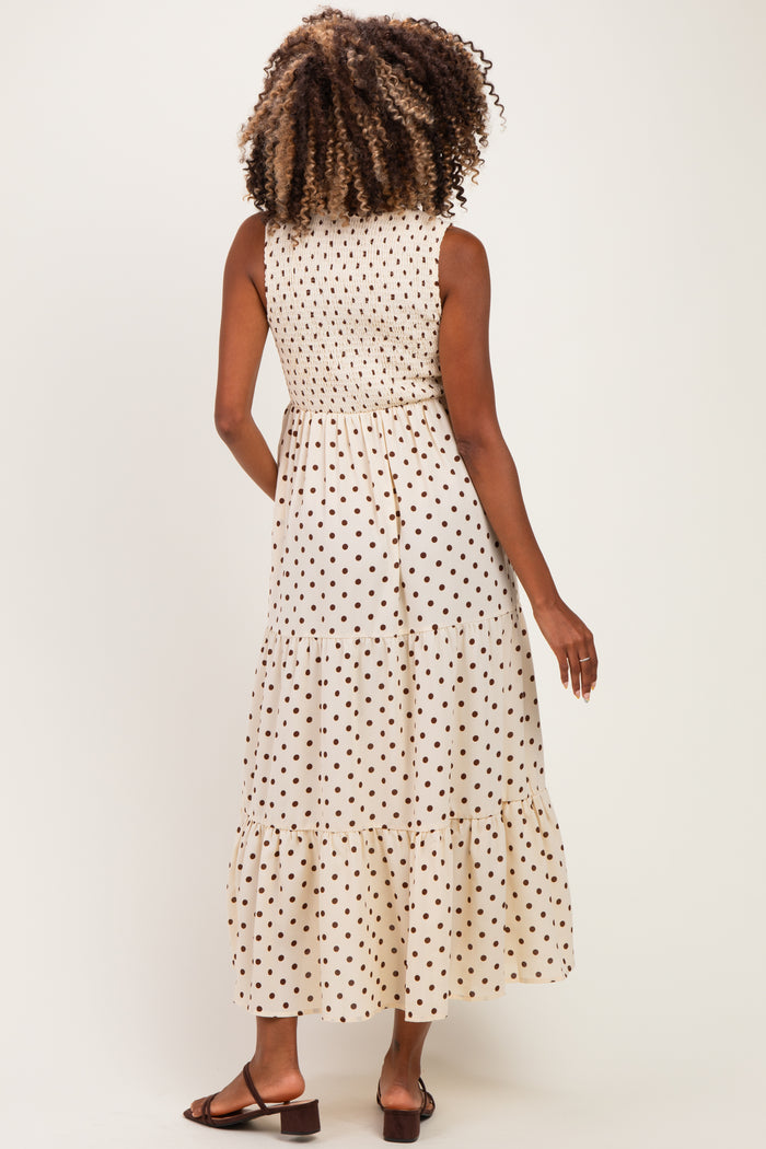 woman wearing a beige maternity dress with black polka dots and a tiered hem, showing the back view