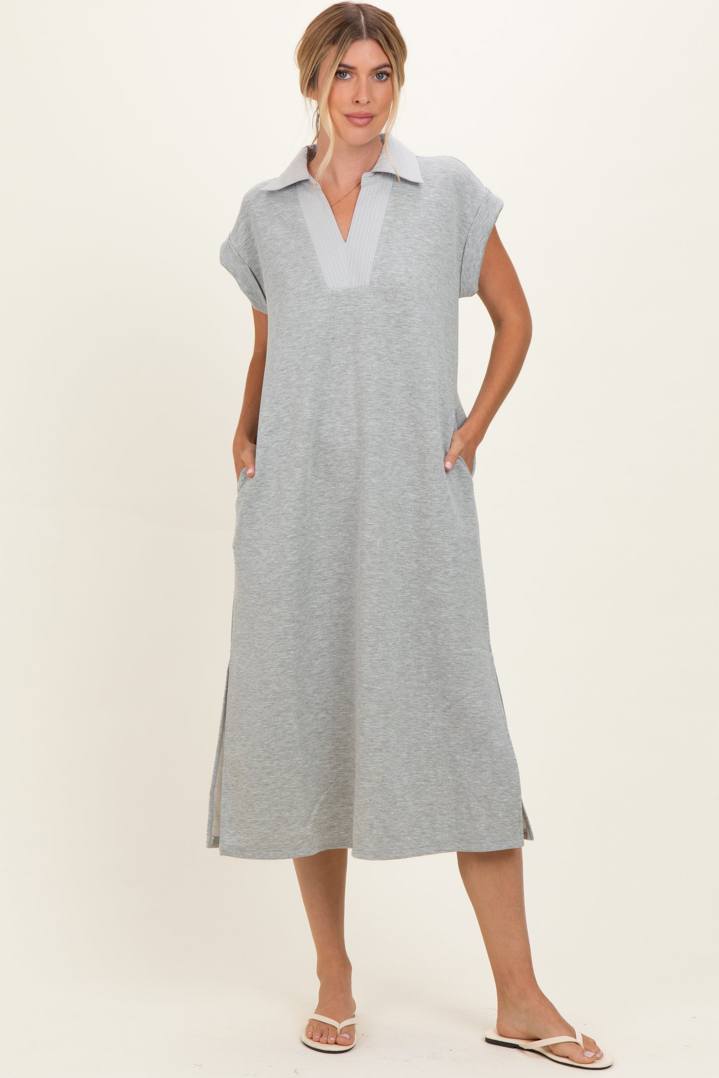 woman wearing a gray short sleeve collared dress with side pockets and a relaxed fit