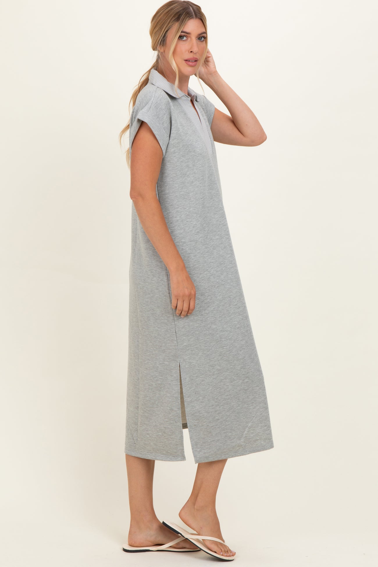 woman wearing a gray short sleeve midi dress with a collar and side slits, posed sideways