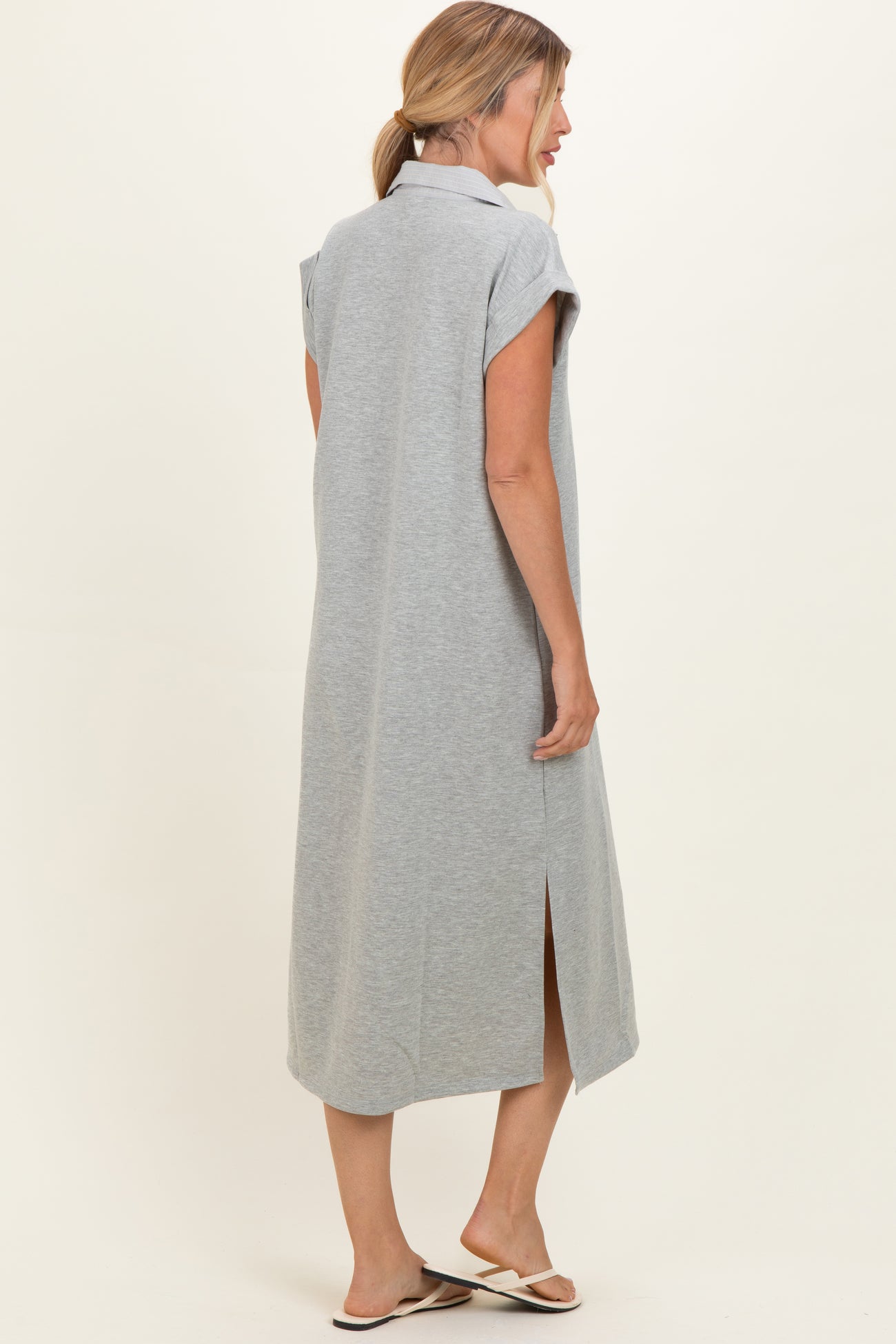 woman wearing a gray maxi dress with short sleeves and side slits, seen from the back