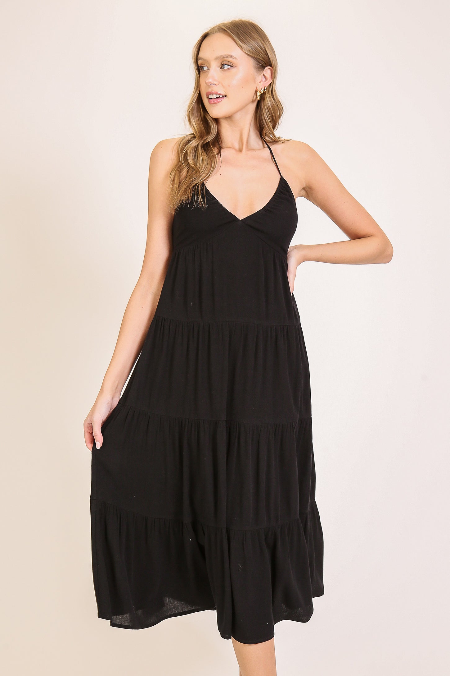 woman wearing a black tiered maxi dress with a halter neck and flowy silhouette
