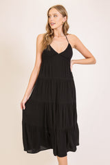 woman wearing a black tiered maxi dress with a halter neck and flowy silhouette
