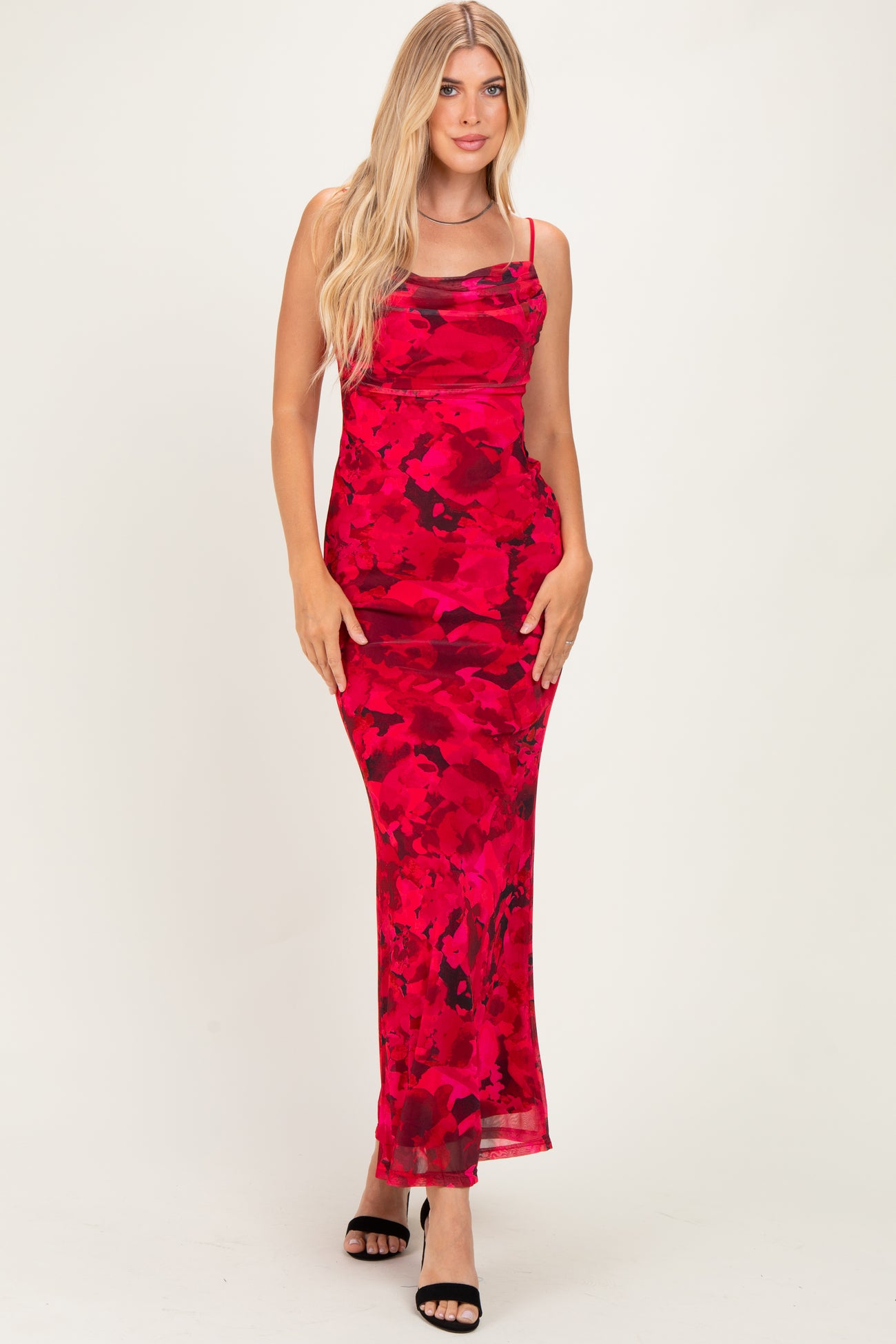 woman wearing a red floral maxi dress with spaghetti straps and a form-fitting style, standing on a white background