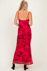 woman wearing a red floral maxi dress with thin straps, showcasing the back design and flowing fabric