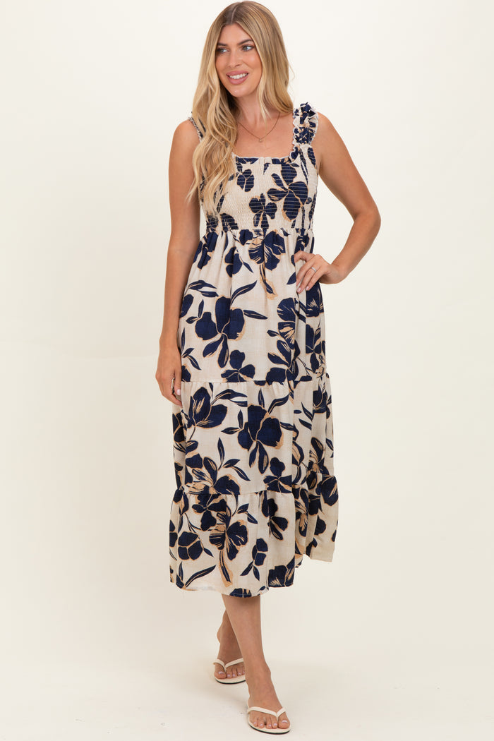 woman wearing a floral print maxi dress with navy blue flowers on a cream background and ruffled straps