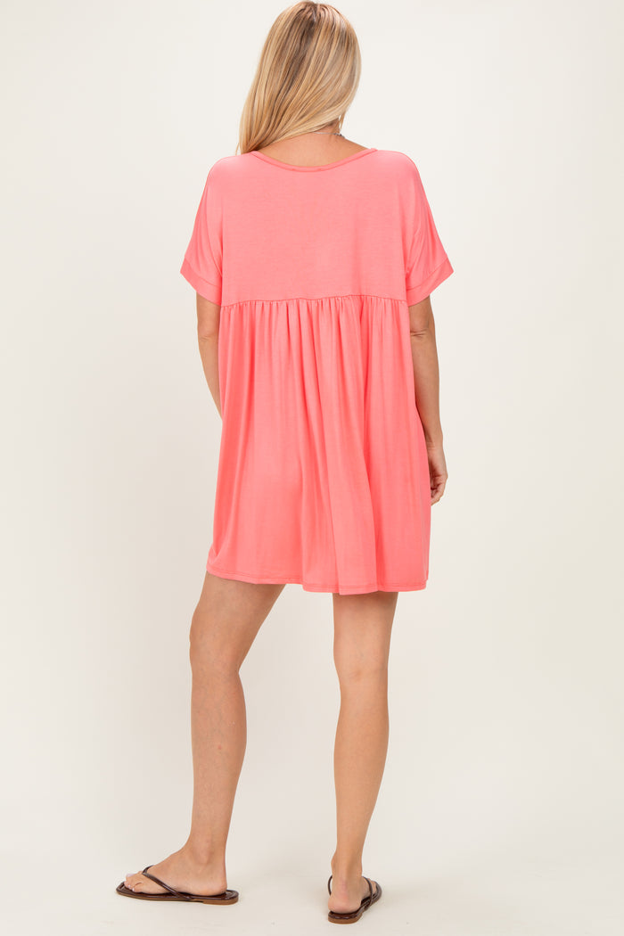 woman wearing a relaxed fit coral short sleeve dress with a tiered skirt and a scoop back