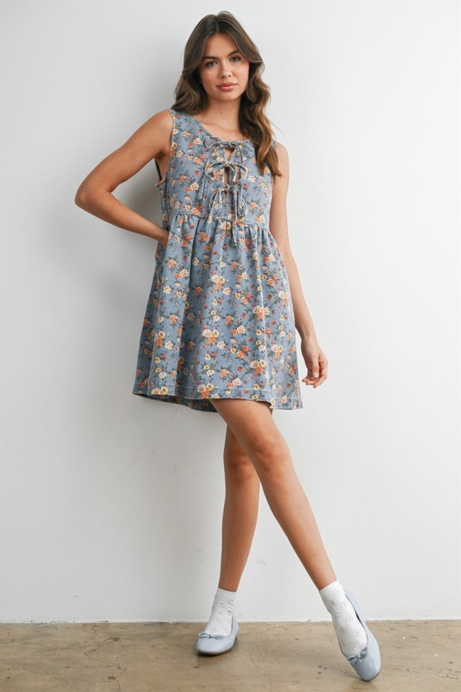 woman wearing a grey floral sleeveless dress with a tie detail and a flared skirt