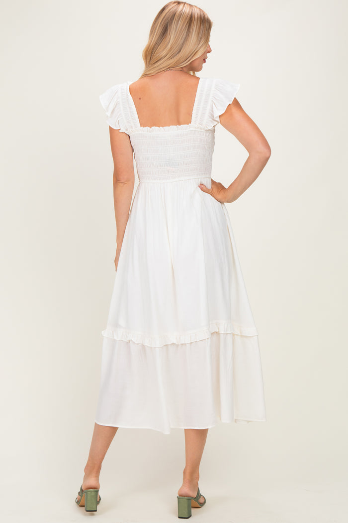 woman wearing a white midi dress with ruffled sleeves and a smocked bodice, showing the back view