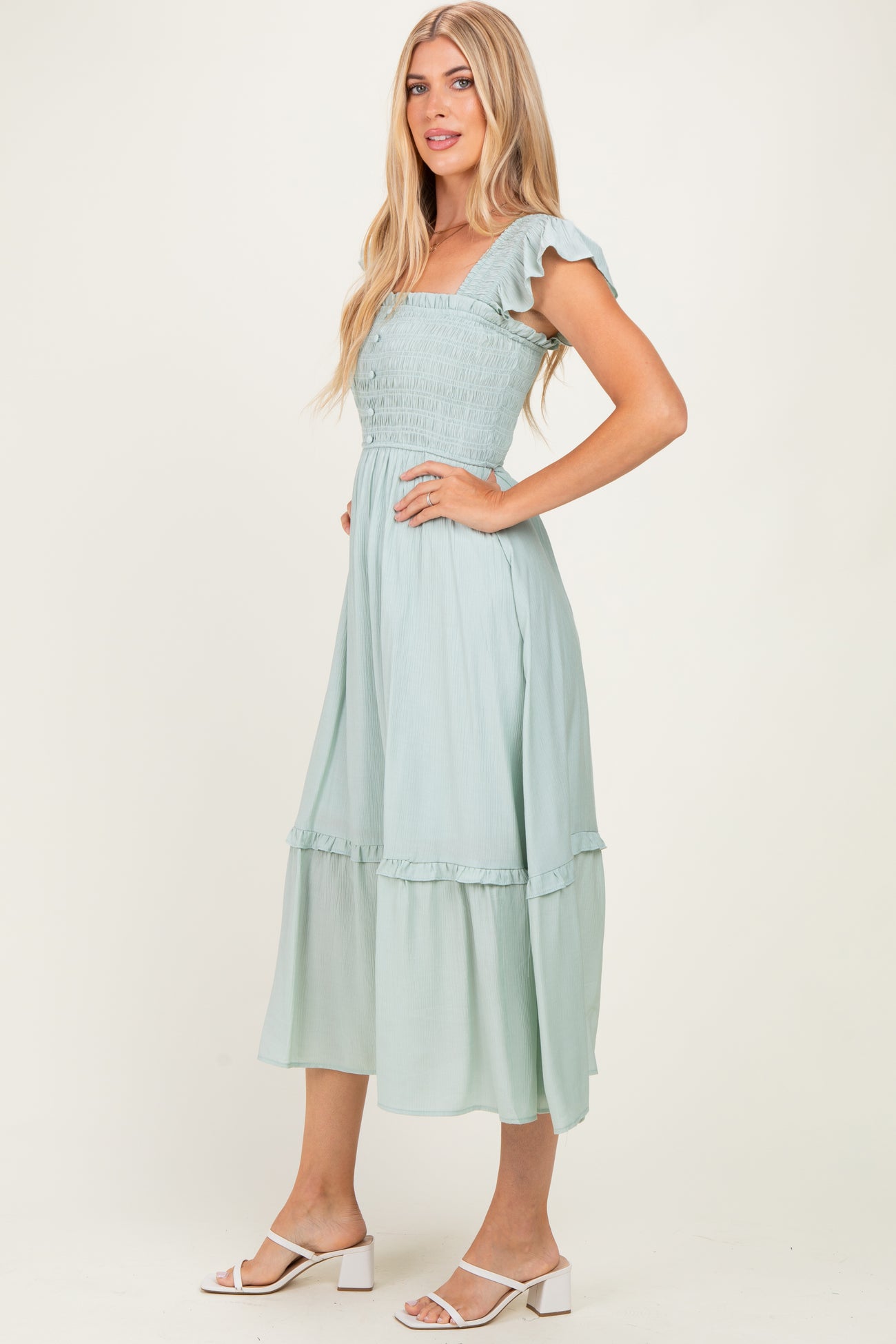 woman wearing a light green midi dress with ruffled sleeves and a tiered skirt