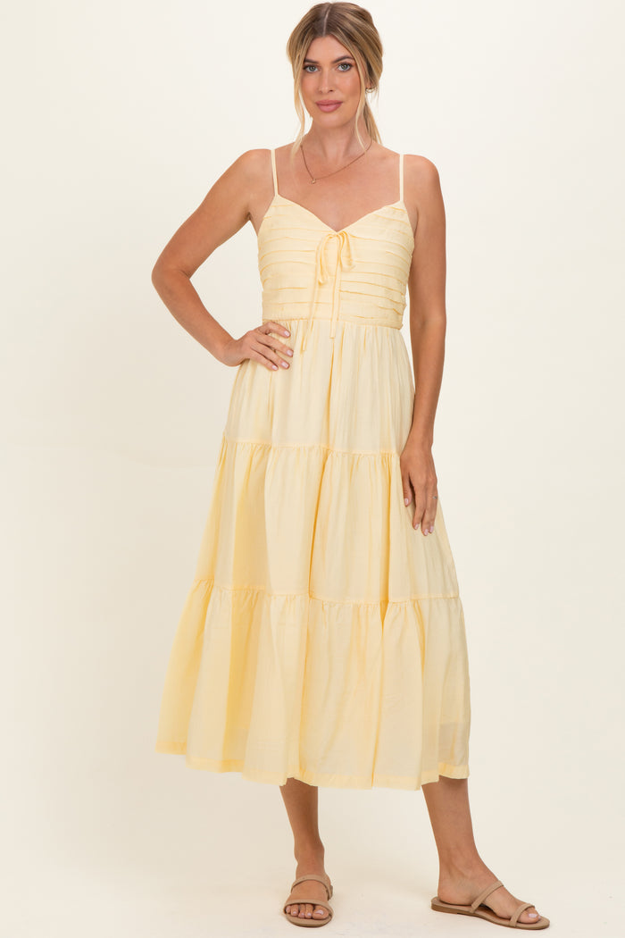 woman wearing a yellow tiered maxi dress with a tie front and spaghetti straps