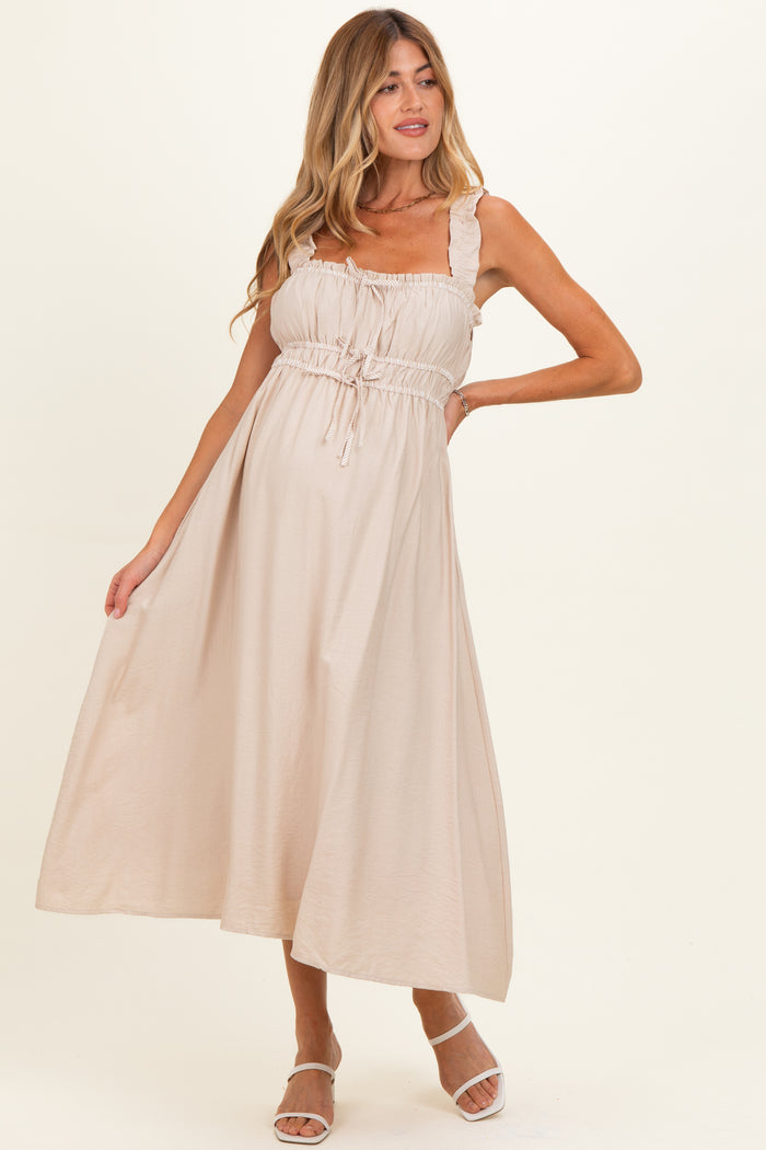 woman wearing a light beige maternity maxi dress with ruffled straps and an adjustable drawstring waist