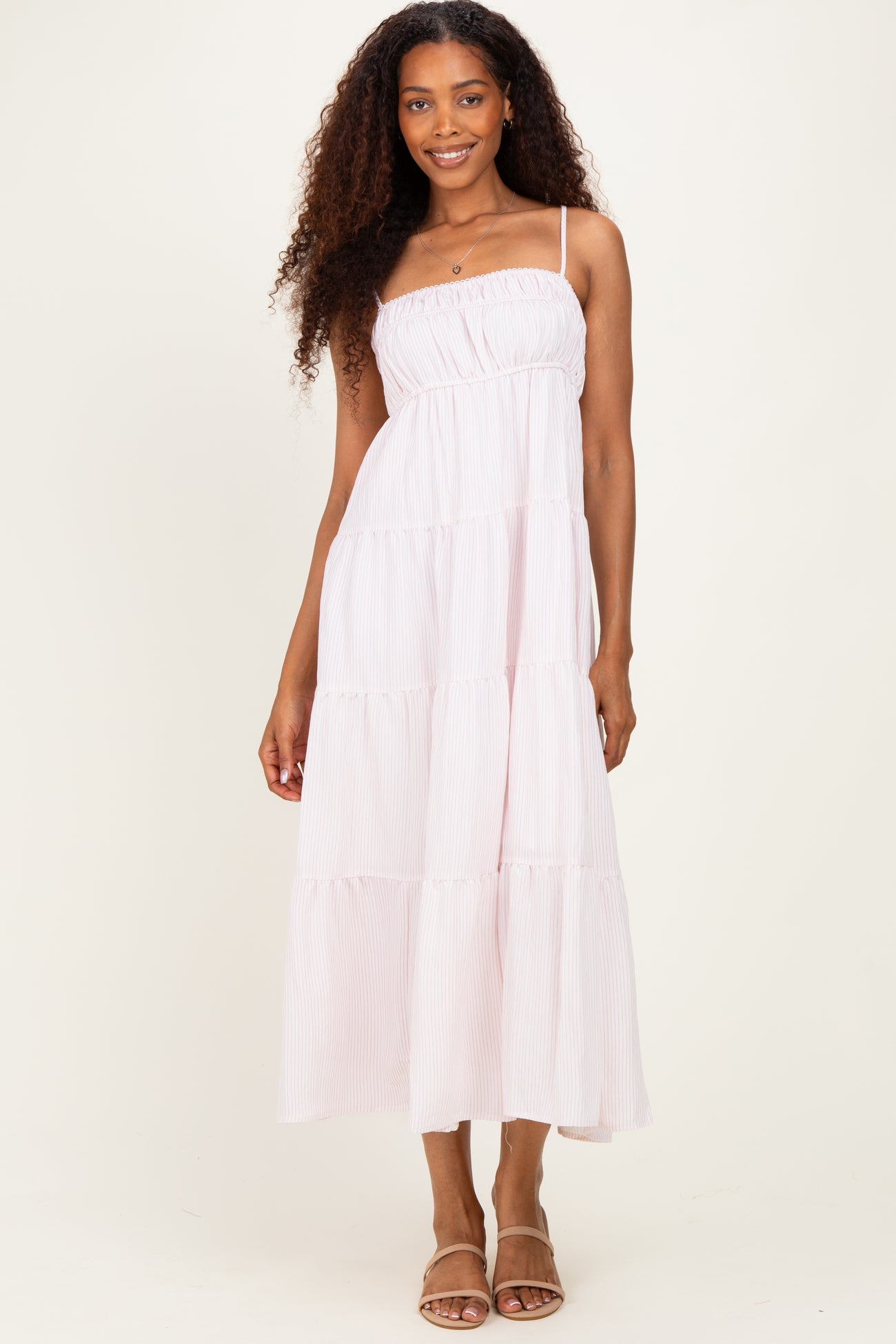 woman wearing a light pink tiered maxi dress with spaghetti straps and a smocked bodice