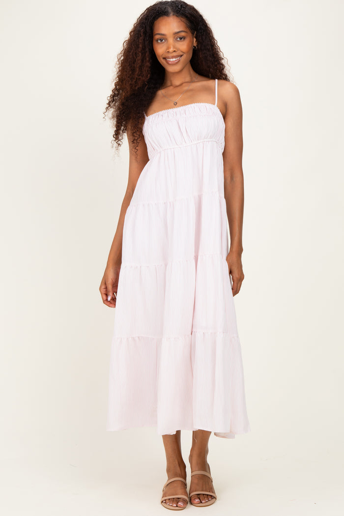 woman wearing a light pink tiered maxi dress with spaghetti straps and a smocked bodice