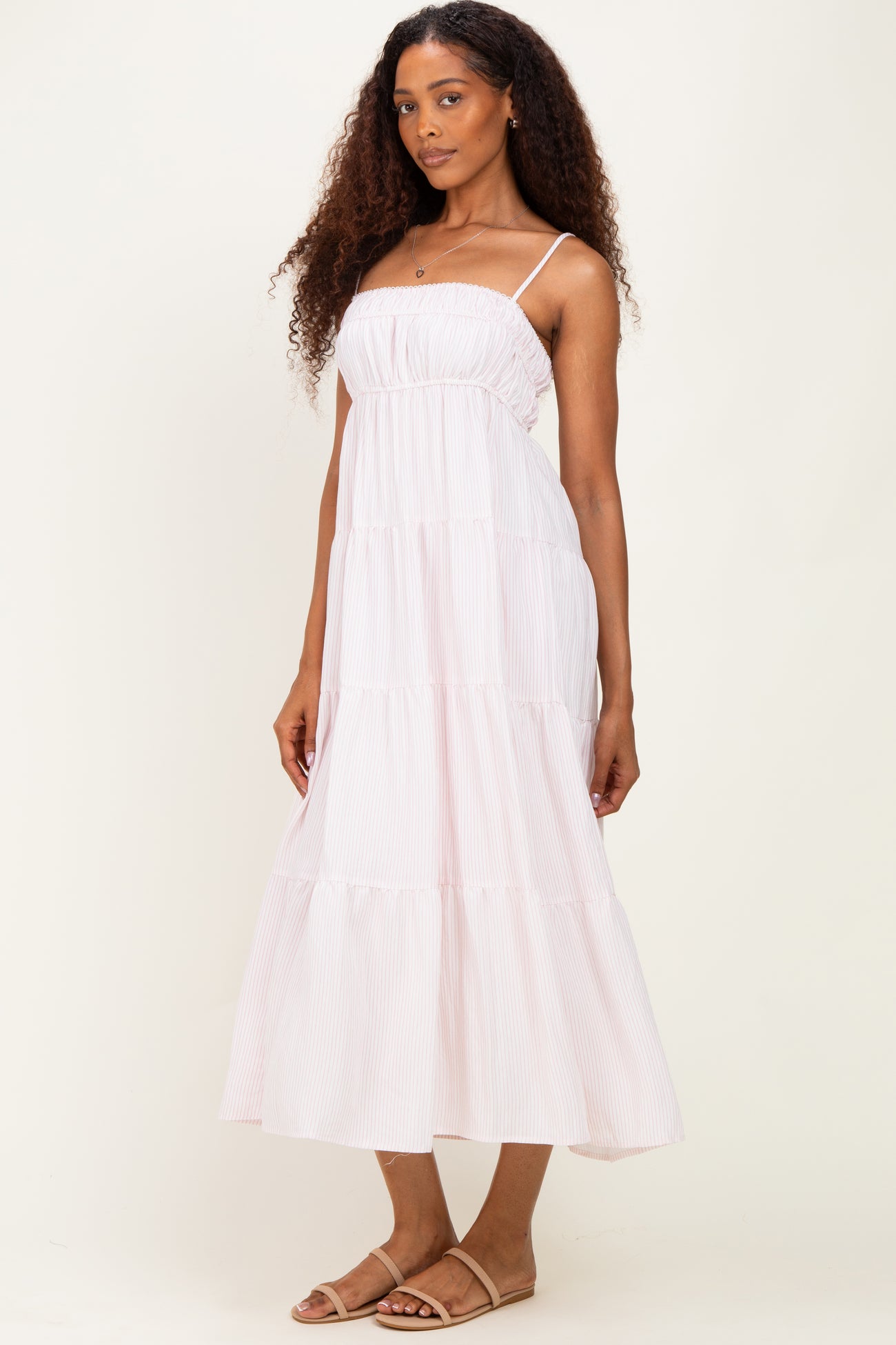 woman wearing a light pink tiered maxi dress with adjustable spaghetti straps and a relaxed fit