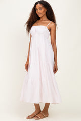 woman wearing a light pink tiered maxi dress with adjustable spaghetti straps and a relaxed fit