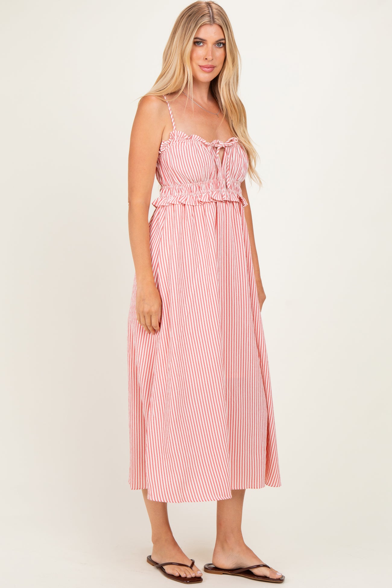 woman wearing a red and white striped midi dress with adjustable straps and a drawstring waist