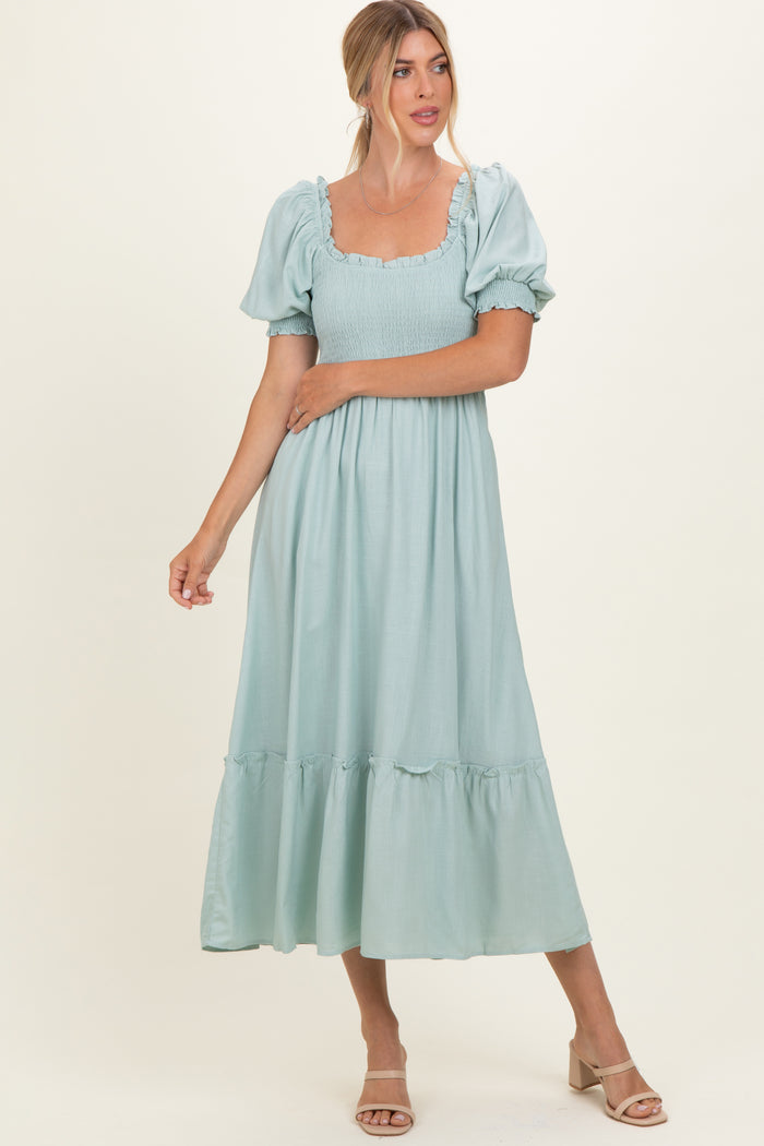 woman wearing a light mint green midi dress with puff sleeves and ruffle hem
