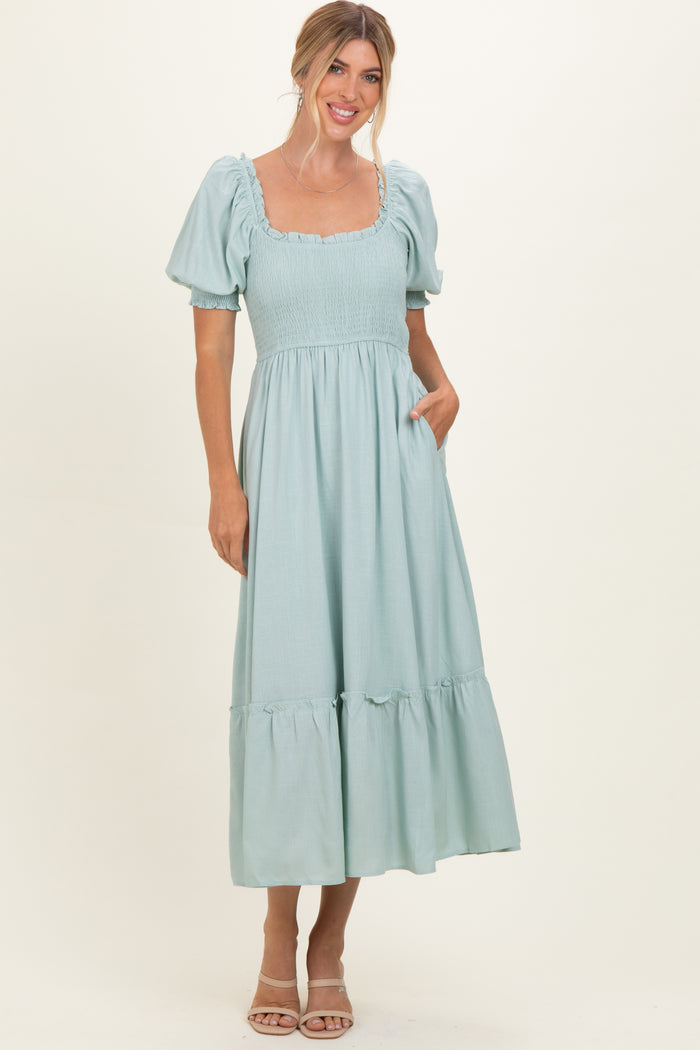 woman wearing a light blue puff sleeve maxi dress with a square neckline and tiered hem with pockets