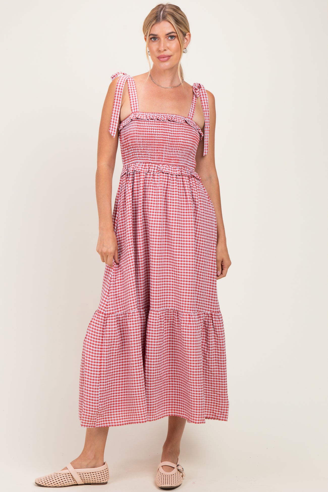 woman wearing a pink and white gingham maxi dress with tie straps and ruffled hem