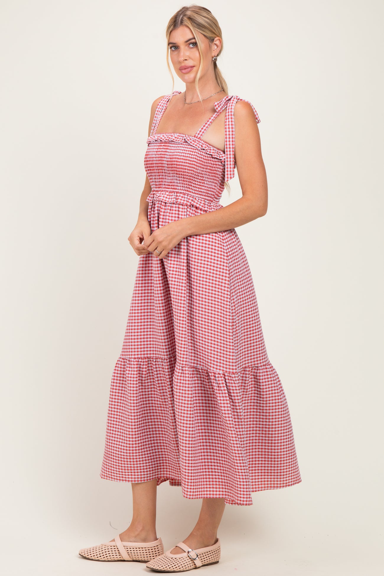 woman wearing a red and white gingham maxi dress with tie straps and a tiered skirt