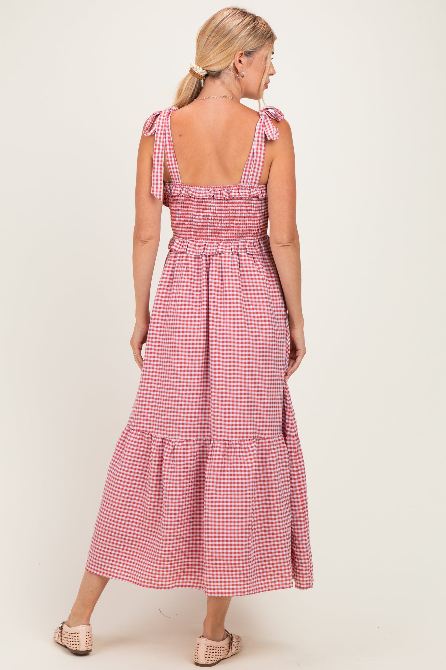 woman wearing a red and white gingham maxi dress with tie shoulder straps and a ruffled hem