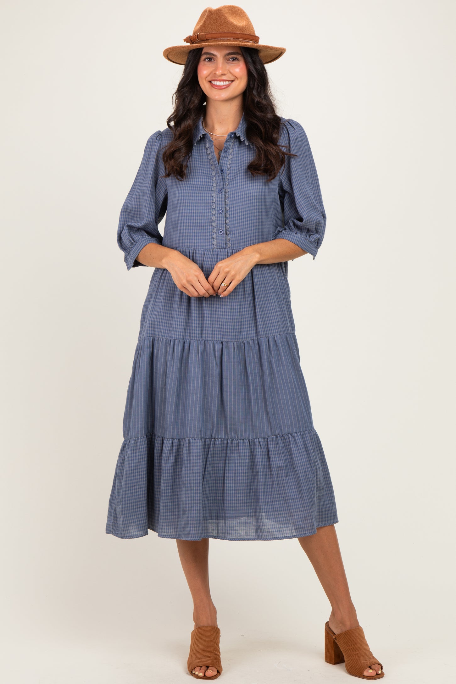 woman wearing a blue gingham tiered midi dress with button details and a brown hat