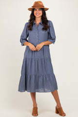 woman wearing a blue gingham tiered midi dress with button details and a brown hat