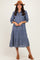 woman wearing a blue gingham tiered midi dress with button details and a brown hat
