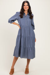woman wearing a blue checkered midi dress with puff sleeves and tiered skirt, standing in a relaxed pose