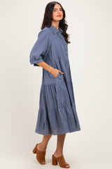woman wearing a blue checkered midi dress with a collared neckline and tiered ruffle detail, styled with brown heeled mules