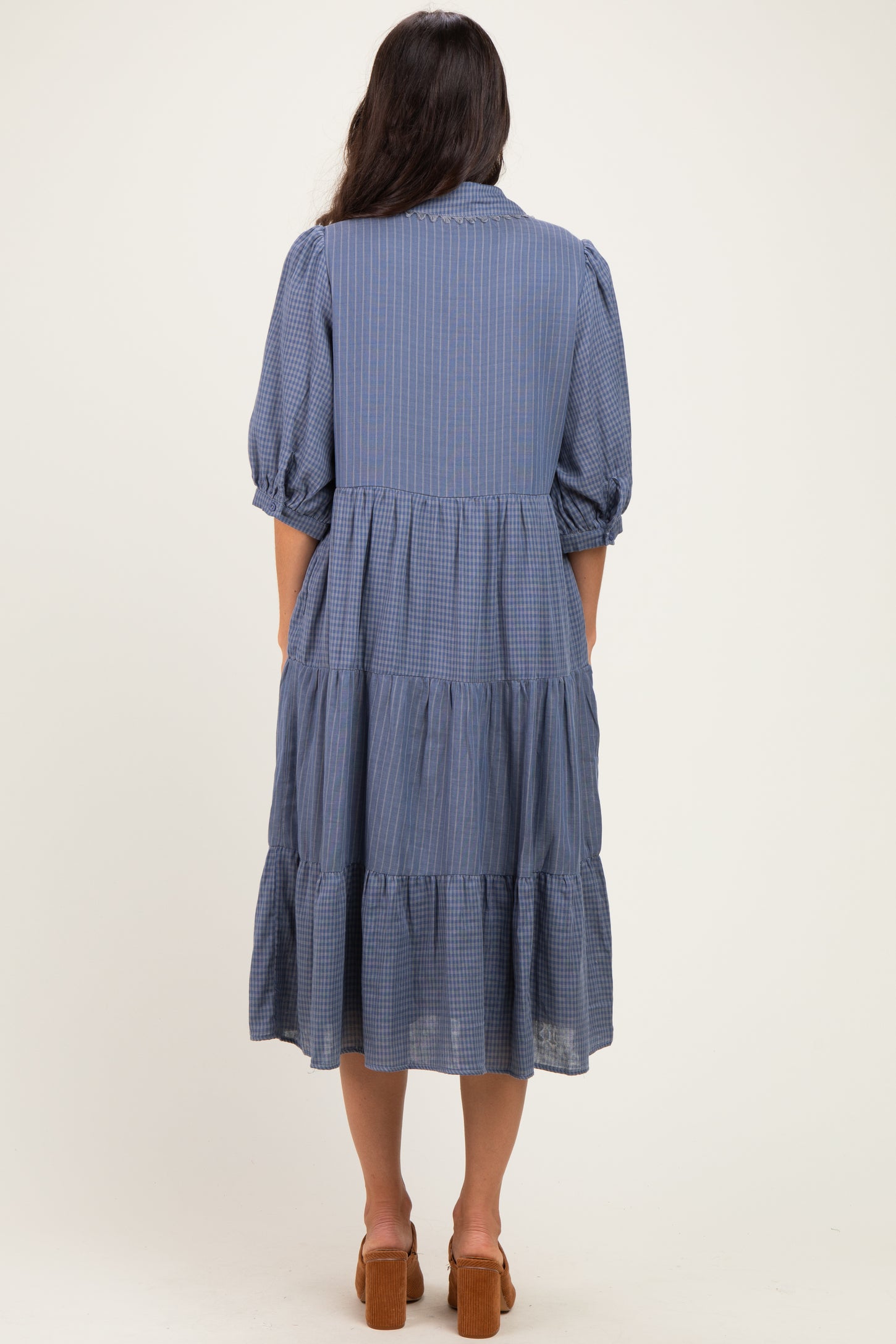 woman wearing a blue checkered midi dress with puff sleeves and tiered skirt, shown from the back