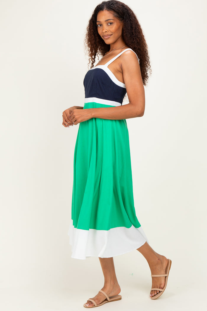 woman wearing a color-blocked maxi dress with a navy top, green midsection, and white bottom, styled with tan sandals