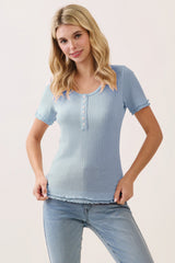 woman wearing a light blue short sleeve top with a button front and scalloped edges, styled with jeans