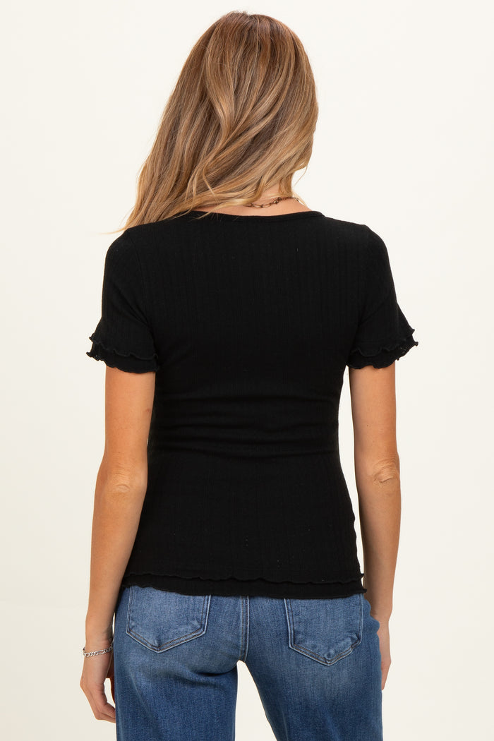 woman wearing a black ribbed maternity top with ruffled short sleeves and a fitted silhouette
