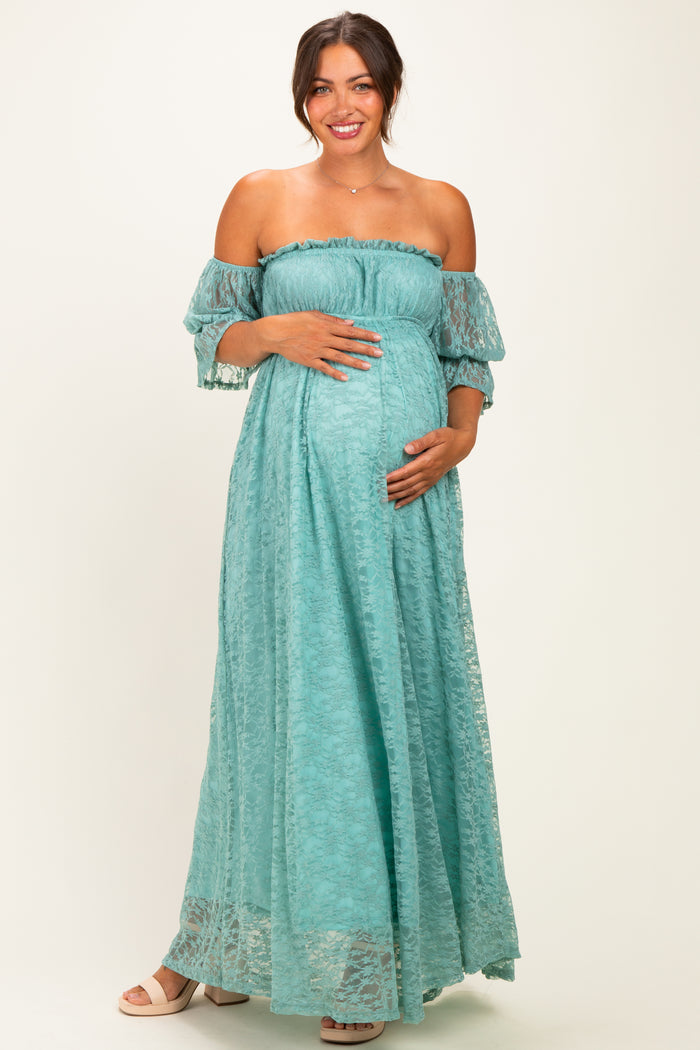 woman wearing a light blue off-the-shoulder maternity maxi dress and holding her baby bump