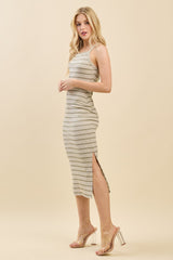 woman wearing a striped midi dress with a side slit and spaghetti straps, styled with clear heeled sandals